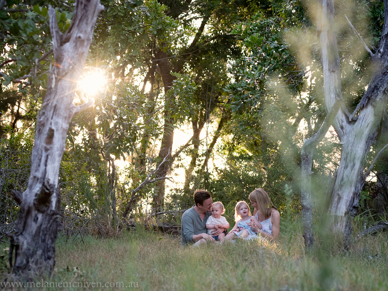 family sitting in grass during a family portrait in Noosa
