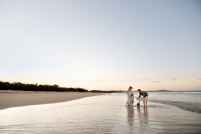 a family playing in the shallow waves at noosa main beach