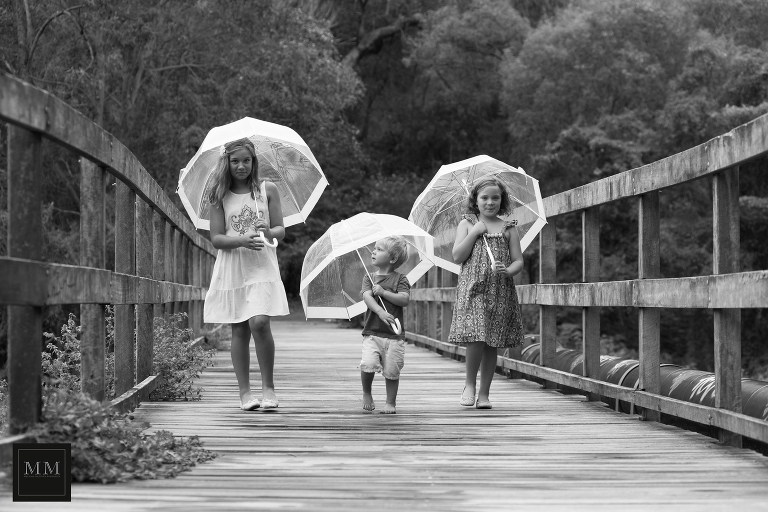 Three children with umbrellas in the rain
