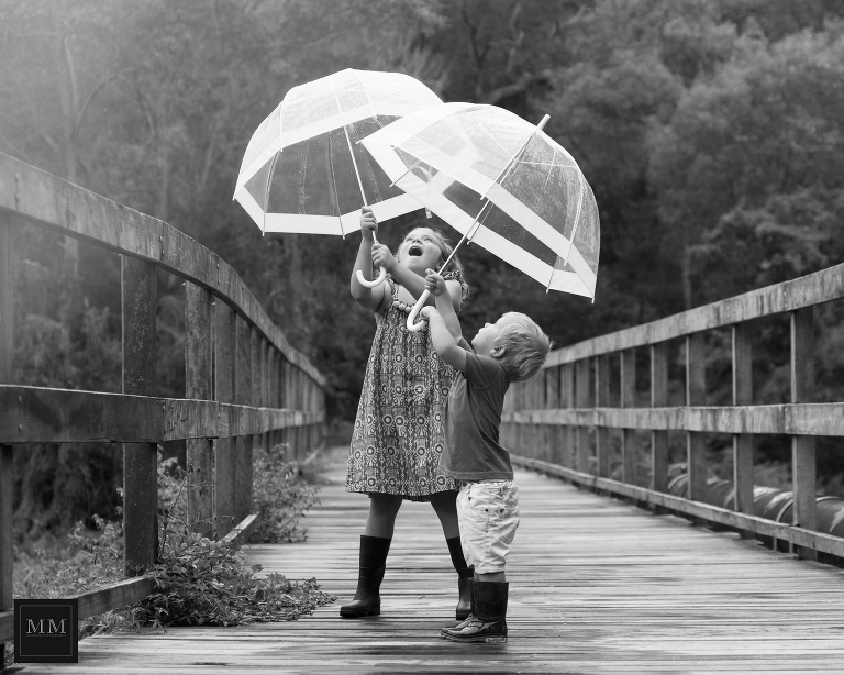 two kids enjoying the rain with umbrellas