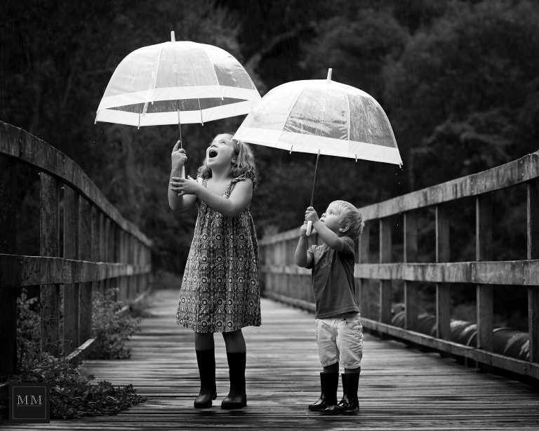 Rainy day portraits with two kids enjoying the rain with umbrellas