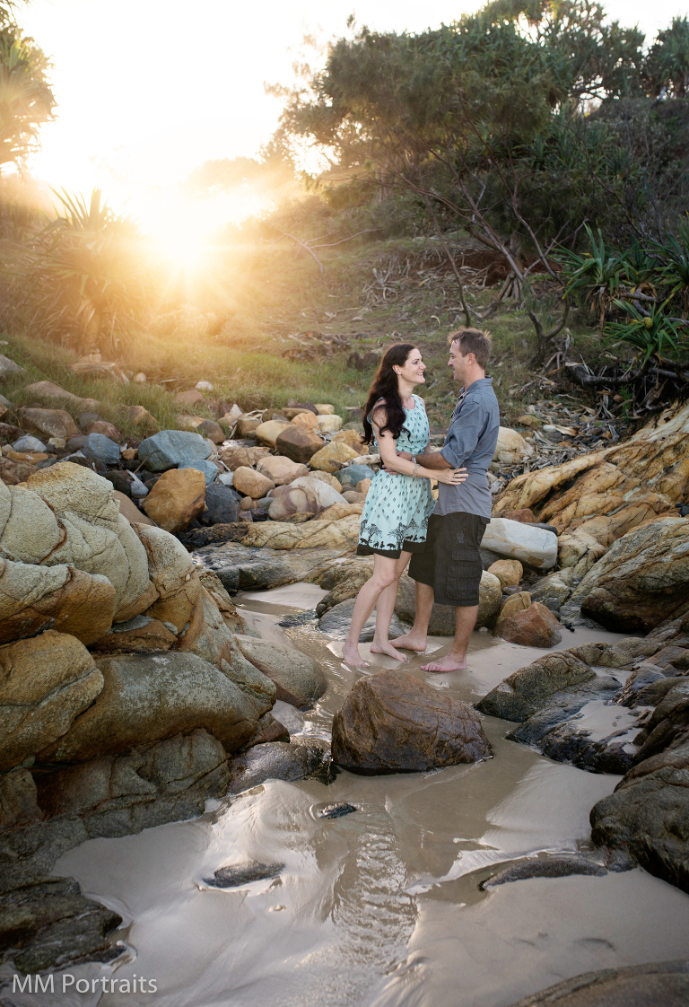 couple on the beach with sun filtering behind the horizon