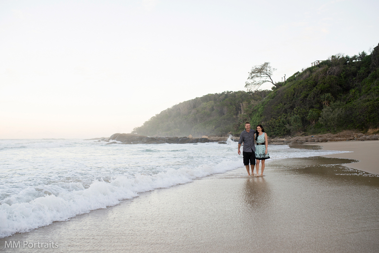 water coming in from beach as couple are walking on sand