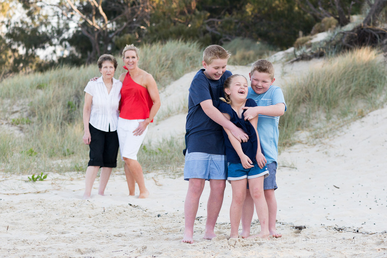 two brother and one sister laughing on the beach 