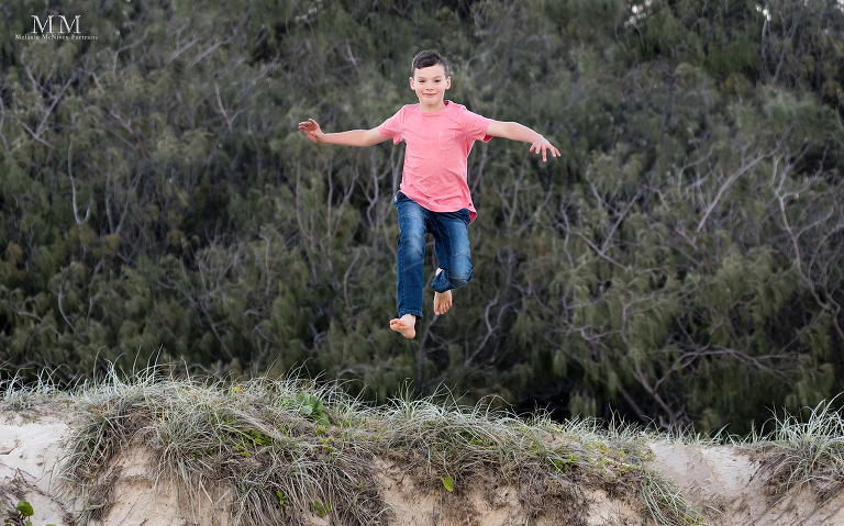 Boy jumping high on beach