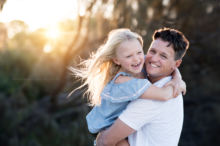 dad cuddling daughter and smiling